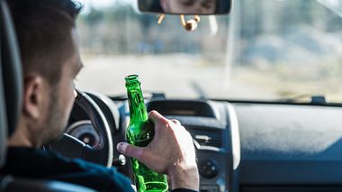 Mann trinkt Alkohol im Auto - Foto: iStock / GregorBister