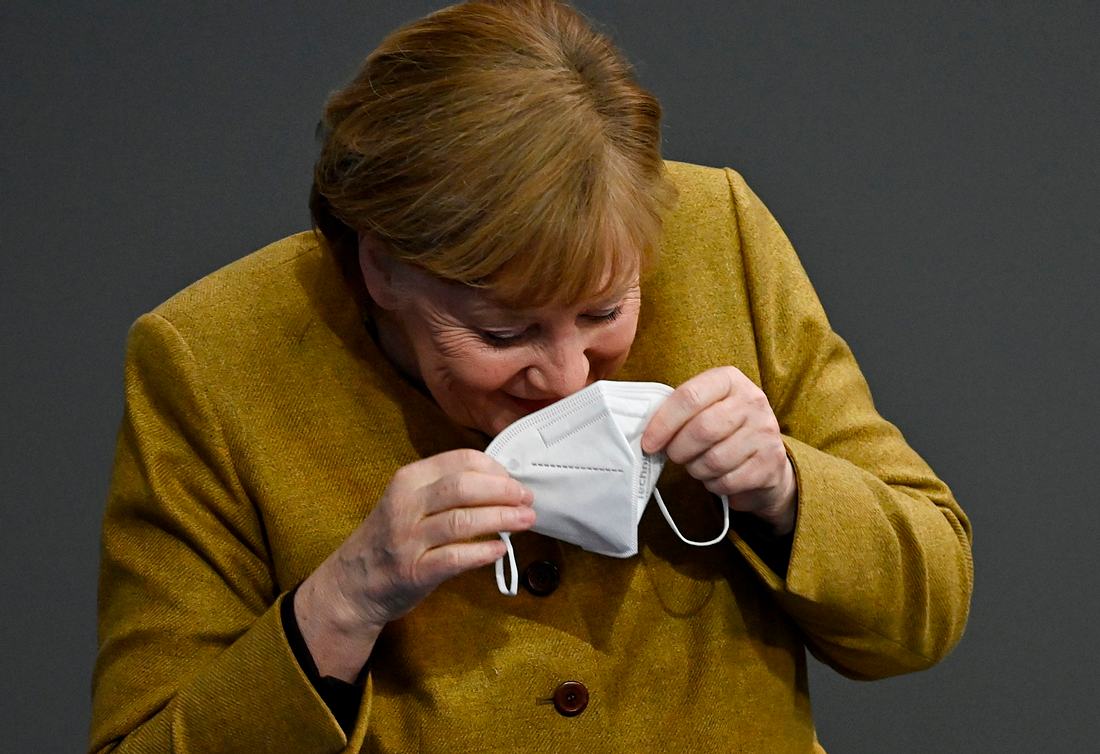 Angela Merkel lacht in ihre Mundschutzmaske hinein