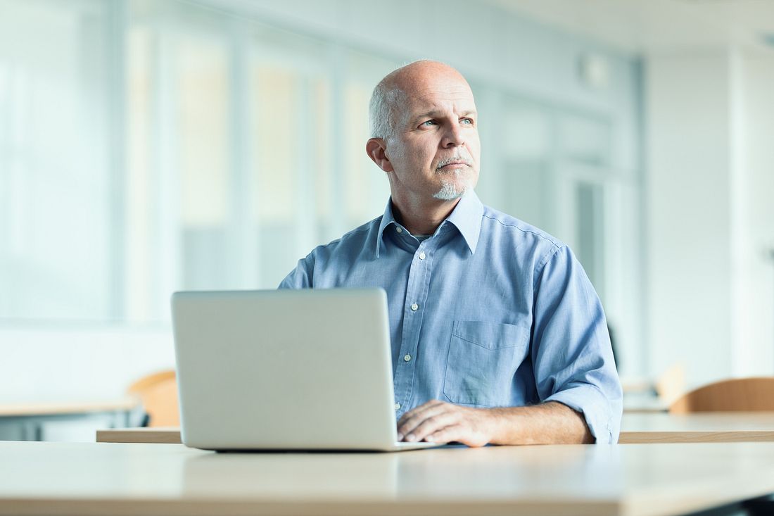 Arbeiten kahlköpfe Männer mehr? Mann mit Glatze vor Laptop