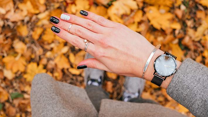 Frauenhand mit einem silbernen Armband mit Gravur und schwarzer Armbanduhr um das Handgelenk - Foto: I-Stock/Christina Vartanova