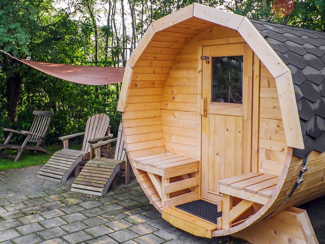 Außensauna kaufen : Die besten Modelle Eine runde Außensauna steht im Garten