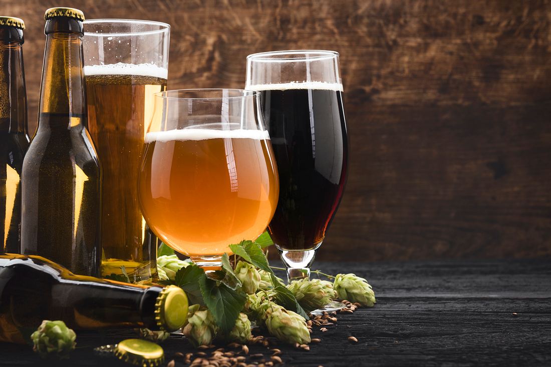 Bierglas mit Gravur Verschiedene Biergläser und Bierflaschen auf einem Holzuntergrund