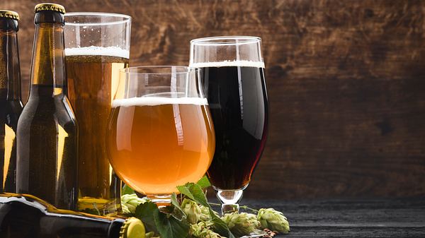 Verschiedene Biergläser und Bierflaschen auf einem Holzboden - Foto: iStock/Rouzes