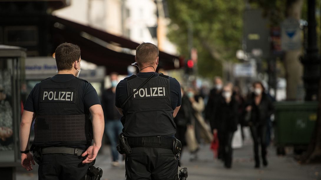 Zwei Polizisten kontrollieren Passanten auf der Straße - Foto: Getty Images / Stefanie Loos