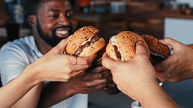 Menschen stoßen mit Burgern an - Foto: iStock / Kobus Louw
