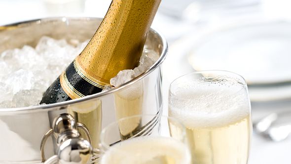 silberner Champagnerkühler mit Crush-Eis gefüllt, Champagnerflasche und zwei gefüllte Gläser zum Anstoßen - Foto: Istock/MarkSwallow