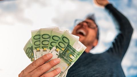 Glücklicher Mann mit fünf 100-Euro-Scheinen in der Hand - Foto: iStock / Kerkez