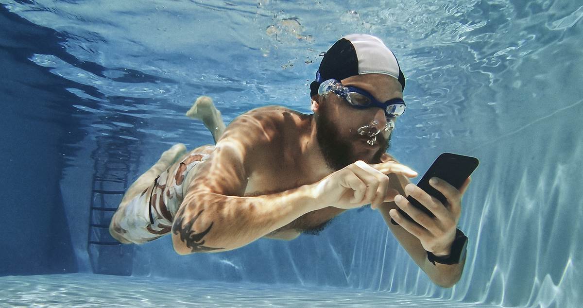 Mann mit Handy im Pool