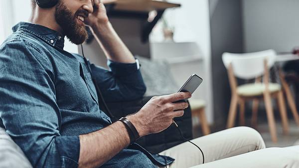 Mann mit Kopfhörern und Smartphone - Foto: iStock / g-stockstudio