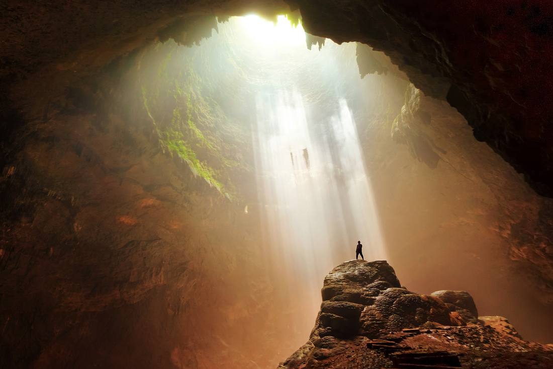 Mensch steht auf einem Felsvorsprung in einer Höhle