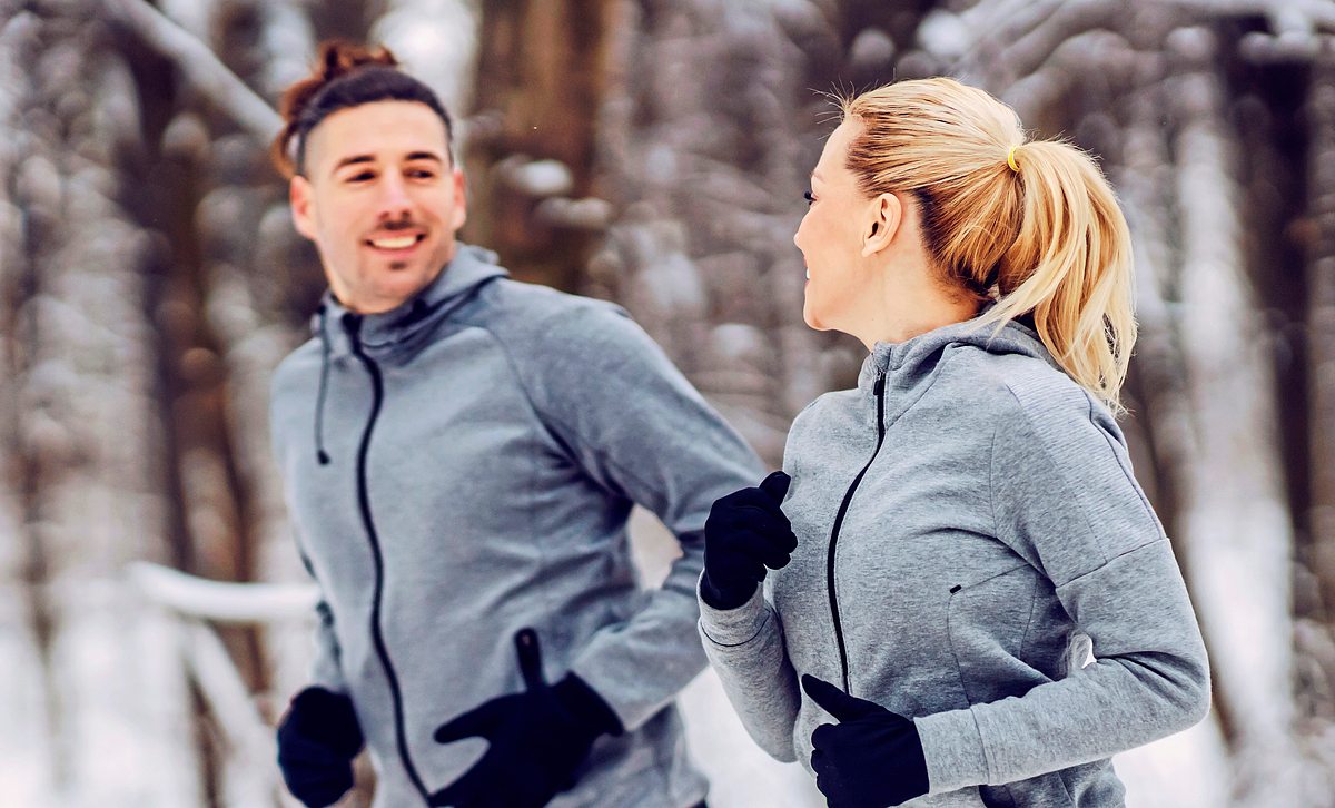 Paar joggt durch verschneiten Wald