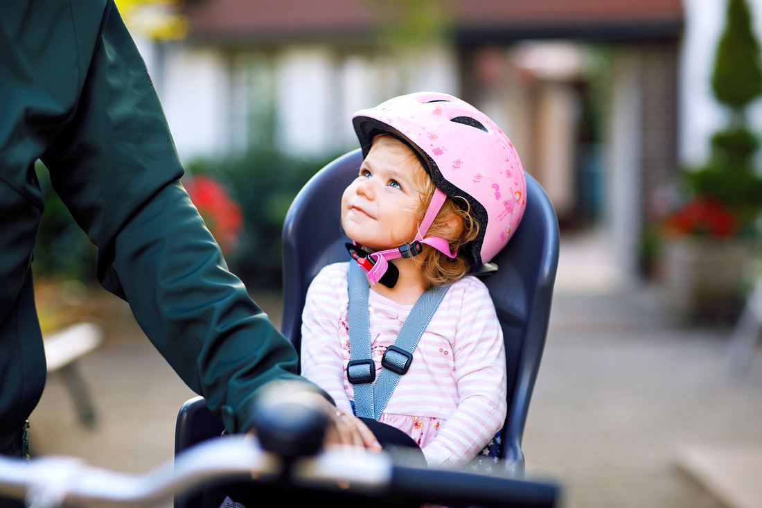 Ein kleines Mädchen sitzt in ihrem Fahrrad-Kindersitz