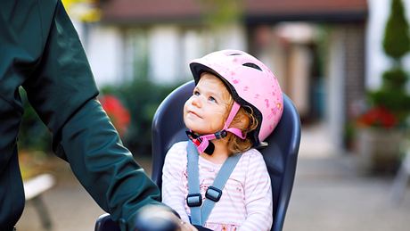 Ein kleines Mädchen sitzt in ihrem Fahrrad-Kindersitz - Foto: iStock/romrodinka