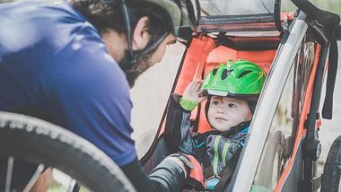 Ein Vater mit seinem Sohn im Fahrradanhänger für Kinder - Foto: iStock/Onfokus