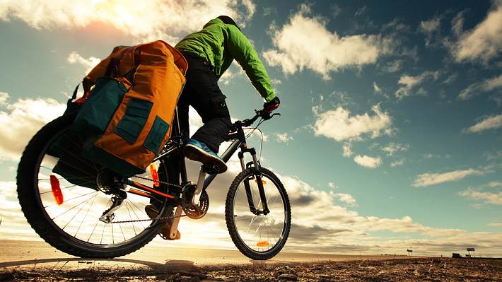 Ein Radler mit einer Fahrradtasche auf dem Gepäckträger in der Natur - Foto: iStock/mihtiander