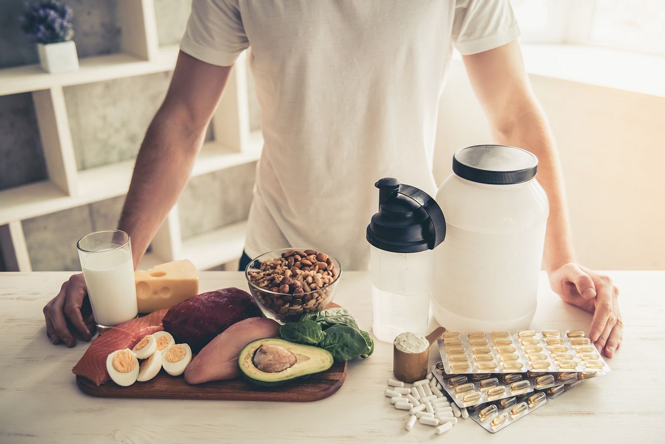Mann mit Fitness-Supplements und Lebensmitteln vor sich Mann mit Fitness-Supplements und Lebensmitteln vor sich