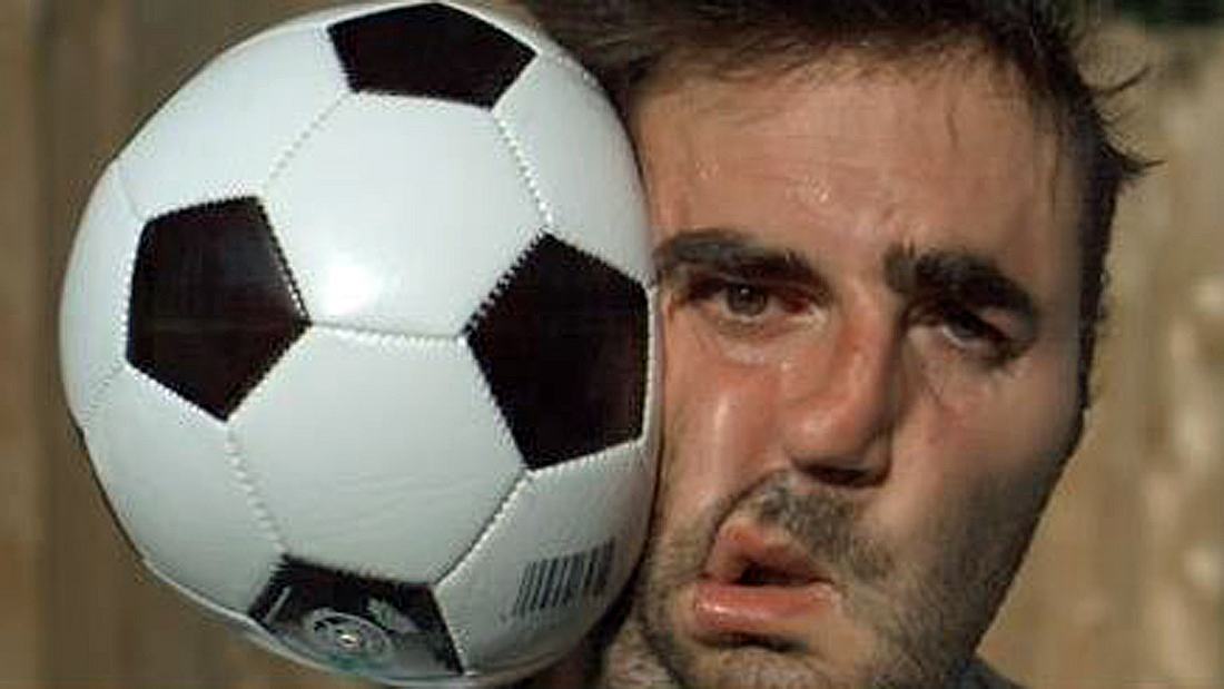 Ein Mann wird von einem Fußball im Gesicht getroffen