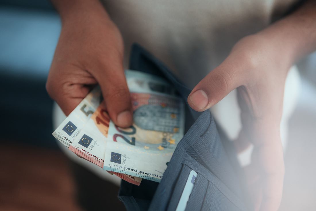 Mann nimmt Geldscheine aus Portemonnaie