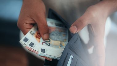 Mann nimmt Geldscheine aus Portemonnaie - Foto: iStock / Alihan Usullu