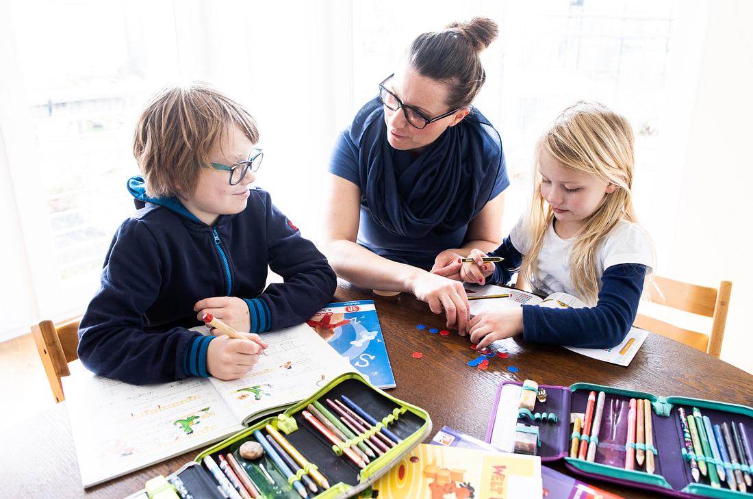 Gemeinsam für die Risikogruppe - So hilfst du deinen Mitmenschen jetzt am meisten! Mutter mit ihren Kindern bei den Schularbeiten Zuhause