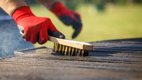 Mann reinigt Grill - Foto: iStock / EXTREME-PHOTOGRAPHER