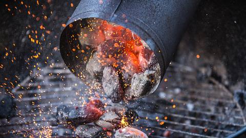 Anzündkamin schüttet durchgeglühte Holzkohle au den Grill - Foto: twpixels