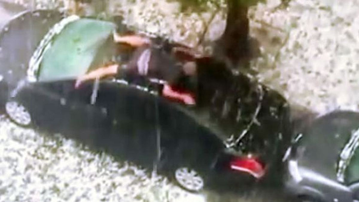 Blech-Bodyguard: Ein Mann schützt sein Auto mit vollem Körpereinsatz vor einem Hagelschauer
