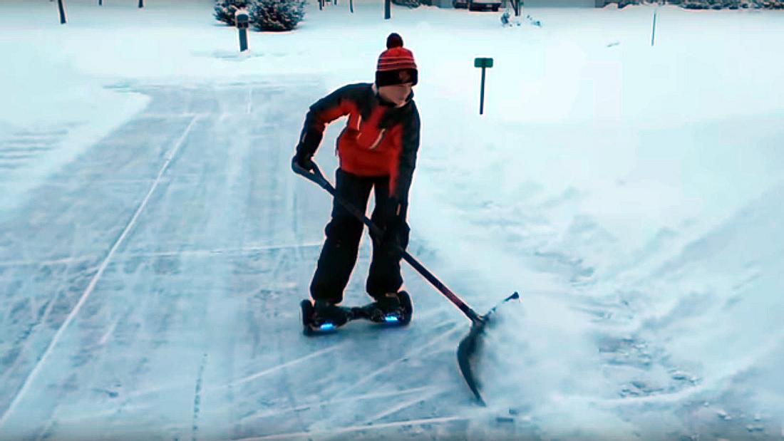 Ein US-Teenager befreit eine Auffahrt mithilfe eines Hoverboards und einer Schneeschippe von Schnee 