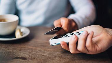 Mann bezahlt kontaktlos mit seiner Kreditkarte