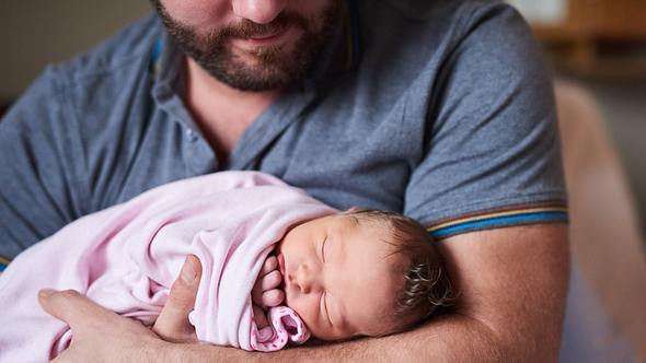 Mann mit Säugling auf Arm - Foto: iStock/Yuri_Arcurs