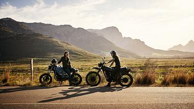 Zwei Motorräder stehen am Straßenrand vor den Bergen. - Foto: iStock/pixdeluxe