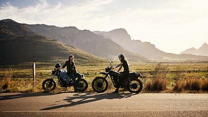 Zwei Motorräder stehen am Straßenrand vor den Bergen. - Foto: iStock/pixdeluxe