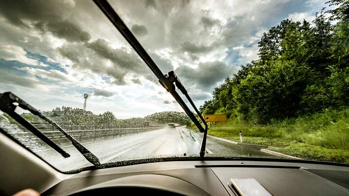 Blick aus der Frontscheibe eines Autos mit Scheibenwischer bei Regen