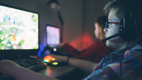 2 Jungs spielen online Games und tragen Headsets. - Foto: iStock/Milan_Jovic