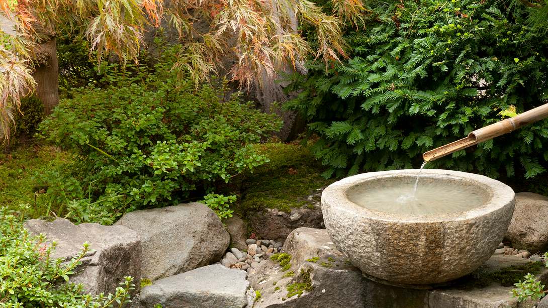 runder Gartenbrunnen aus Granit in idyllischem Garten