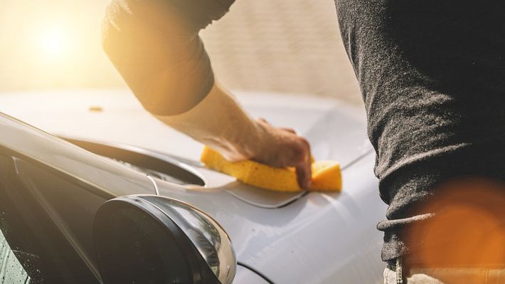 Ein Mann reinigt seine Motorhaube