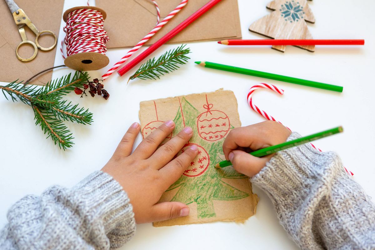 Kinderhände malen einen Weihnachtsbaum