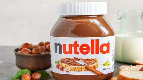 Nutella-Glas, daneben Haselnüsse, Milch und Brotscheiben - Foto: IMAGO / Depositphotos