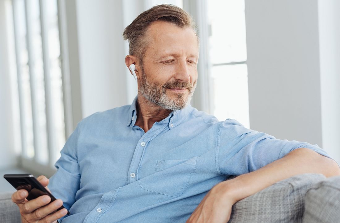 Nokia True Wireless Earbuds Mann mit True Wireless-Kopfhörern im Ohr und Handy in der Hand