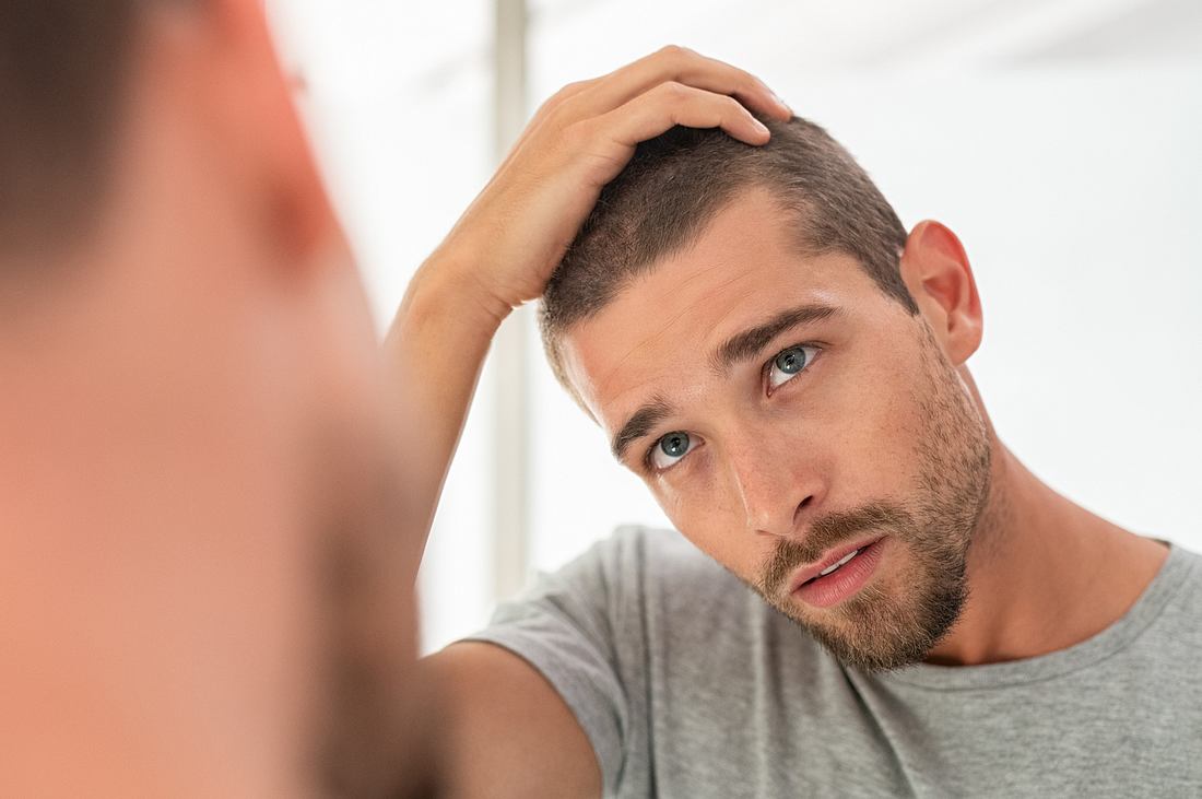 Mann überprüft im Spiegel seine Haare