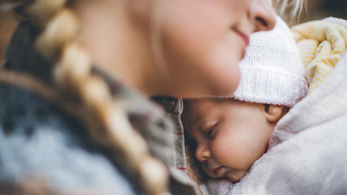 Baby schläft an der Brust seiner Mutter - Foto: istock / Pekic