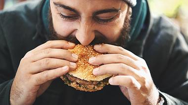 Mann isst Burger - Foto: iStock/gilaxia