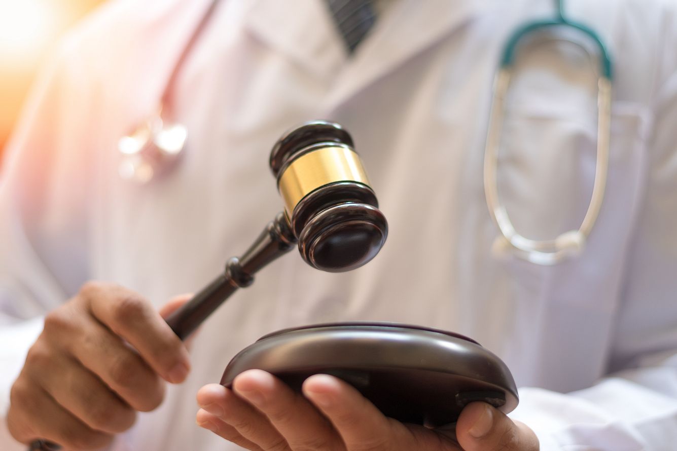 Justiz-Hammer! Corona-leugnende Ärzte kommen vor Gericht Arzt mit Richterhammer