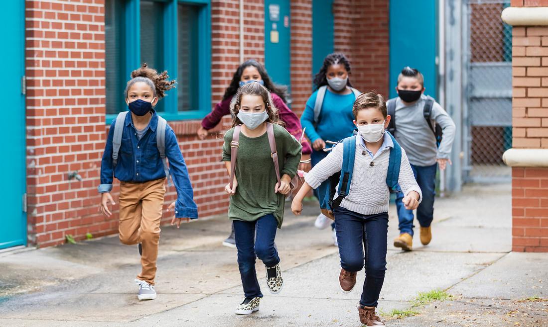 Kinder mit Schutzmaske auf dem Schulhof