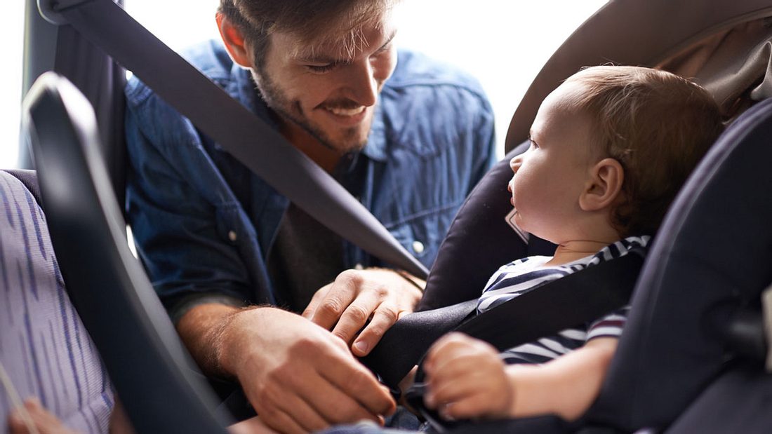 Vater schnallt sein Kleinkind an Vater schnallt sein Kleinkind an