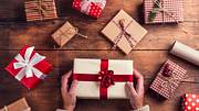 Zahlreiche Weihnachtsgeschenke liegen auf einem Holztisch - Foto: iStock/Halfpoint