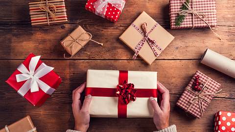 Zahlreiche Weihnachtsgeschenke liegen auf einem Holztisch - Foto: iStock/Halfpoint