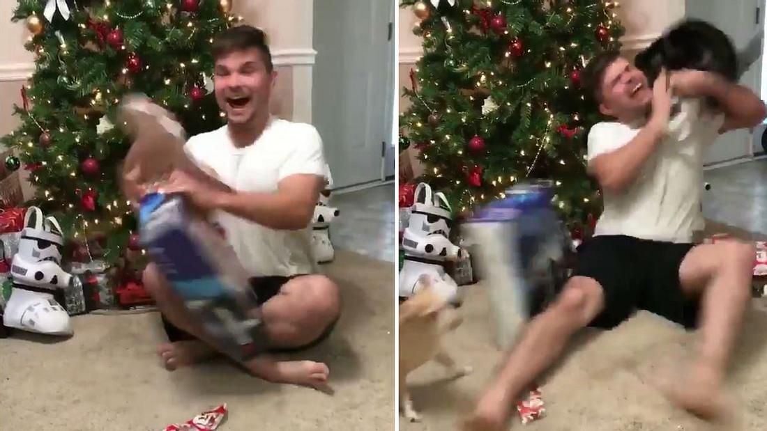 Eine Katze attackiert einen mann, der zu Weihnachten eine PlayStation 4 auspackt