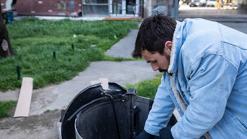 Mann mit Mülltonne - Foto: iStock / Srdjanns74