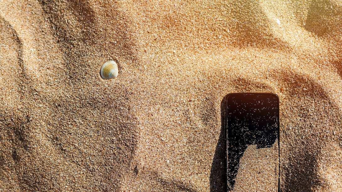 Handy im Sand - Foto: iStock/MartenBG